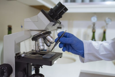 Close up of lab technician by placing a sample on microscope.