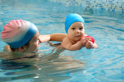 Early age swimming in pool. baby boy trained to swim in water. happy child with trainer woman in