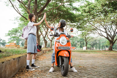 Rear view of woman with arms outstretched standing on footpath
