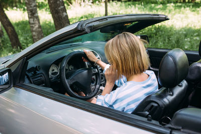 A woman is driving a convertible car. summer road trip to nature