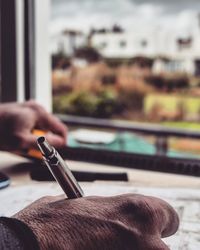 Cropped hand writing with pen in book on table