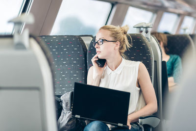 Young woman using mobile phone while sitting in train