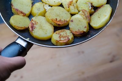 Cropped hand holding potatoes in cooking pan