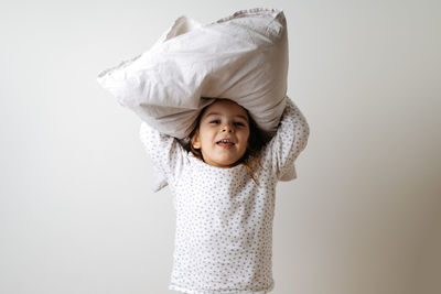 Portrait of cute girl holding pillow on head