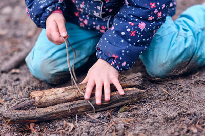 Midsection of girl holding sticks while sitting outdoors