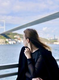 Beautiful young woman looking at sea against sky