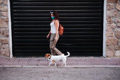 Full length of woman with dog against shutter