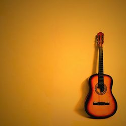 Close-up of guitar with yellow background