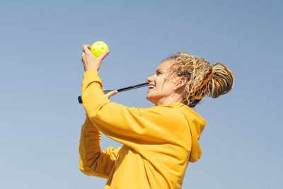 Low angle view of young woman standing against clear sky