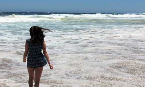 Rear view of woman walking on beach