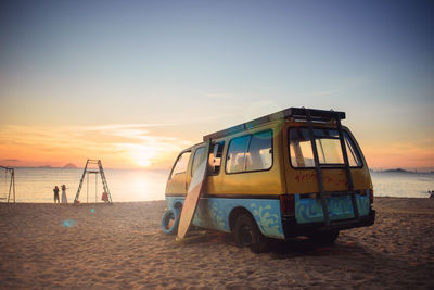 View of bus on beach against sky during sunset