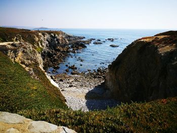 Scenic view of rock formations by sea against clear sky