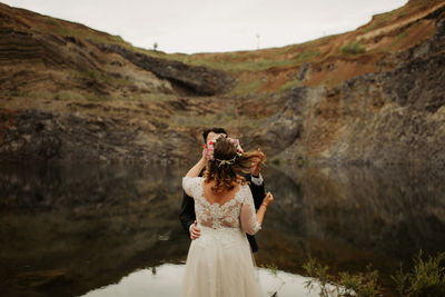 Wedding couple standing by lake against mountain