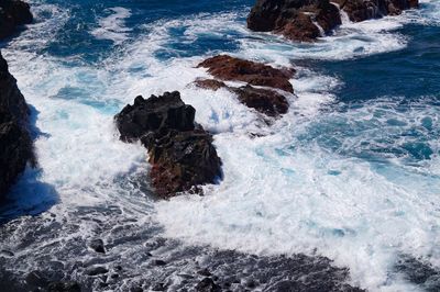 High angle view of waves splashing and crashing  on and over rocks white water surf 