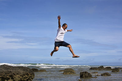 Full length of man jumping at sea against sky