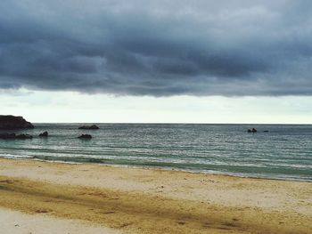 Scenic view of beach against cloudy sky