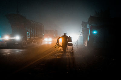 Rear view of man walking on street at night