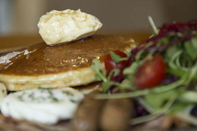 Close-up of pancakes with salad and poached egg in plate on table