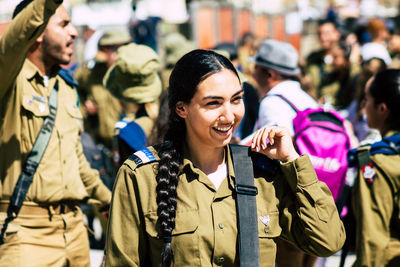 Happy young woman standing against people in city