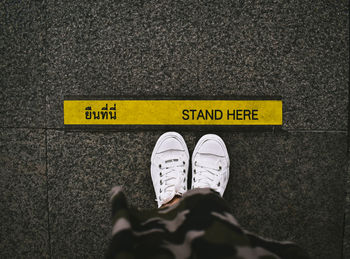 Low section of person standing on road sign