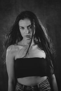 Young woman standing against black background