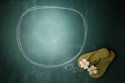 Flip-flop with flower by speech bubble on blackboard