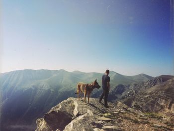 Man standing with dog on top of rock