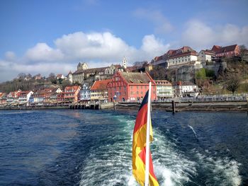 Sailboats in sea by city buildings against sky