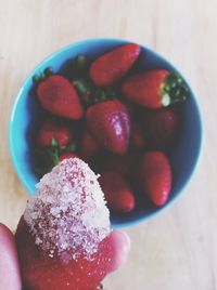 Hand holding strawberry with sugar
