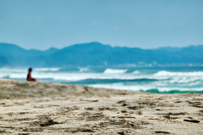 Rear view of man on beach against sky