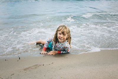 Young girl laying in the water at the beach smiling