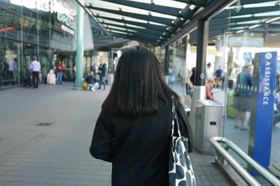 Rear view of women standing on footpath