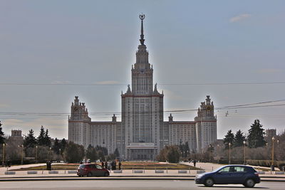 Cars on road by buildings against sky