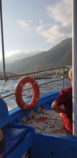 Man on boat in sea against mountains