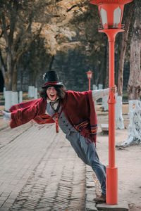 Portrait of man cosplaying mad hatter spinning around lamp post