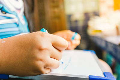 Close-up of boy holding hands on table