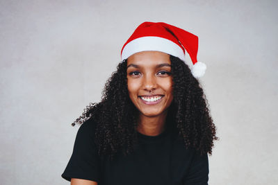 Portrait of smiling young woman wearing santa hat against white background