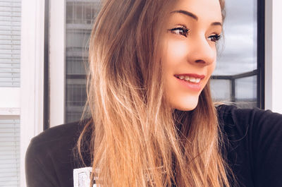 Portrait of beautiful young woman looking through window