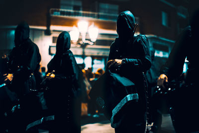 Rear view of people walking on illuminated city at night