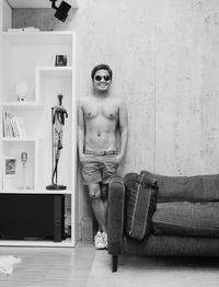Portrait of young man standing against wall at home