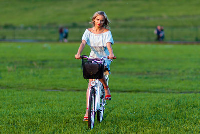 Full length of woman riding bicycle on field