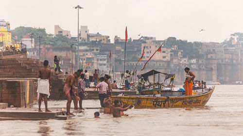 People on boats in sea against city