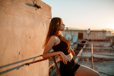 Woman with arms raised against sky