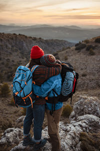 Couple embracing while standing on mountain peak during sunset