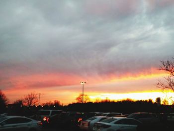 Cars on road against sky at sunset