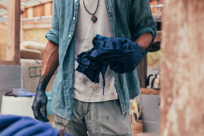 Midsection of man dyeing clothe in factory