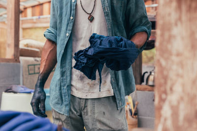 Midsection of man dyeing clothe in factory