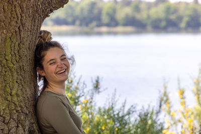 Portrait of young woman standing against lake