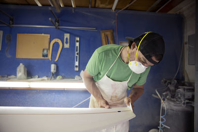 Worker making surfboard in workshop