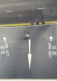 High angle view of man walking by arrow sign on road